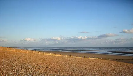 A shingle beach with groynes stretching into the sea
