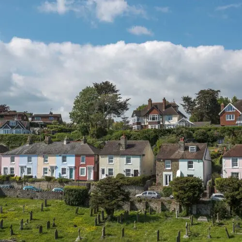 Colourful houses sit next to each other with a cemetery in the foreground