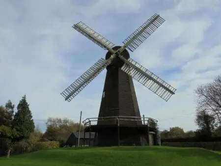 A black weatherboarded windmill with white wooden sails