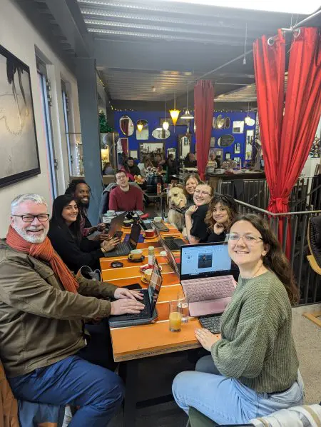 A group of smiling local professionals attending at flexible Work From Home Folk community group in a coffee shop in Folkestone