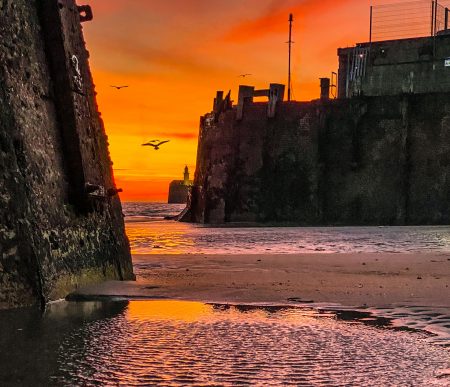 A rippling puddle of water in a dry harbour at sunset