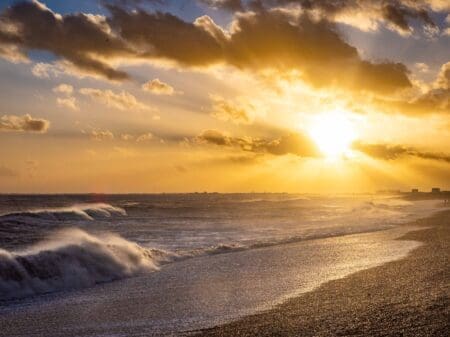A shingle beach with waves crashing against the shore.
