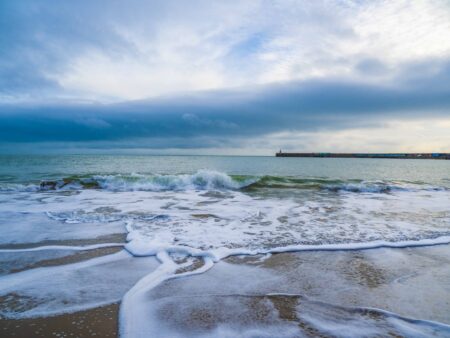 Foamy sea with a harbour arm in the background