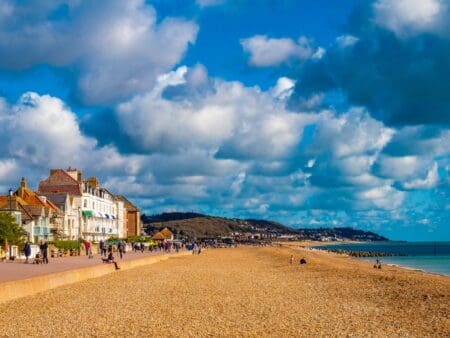 A shingle beach with a promenade and houses on the left side