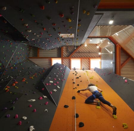A view up a tall climbing wall with a climber on the wall