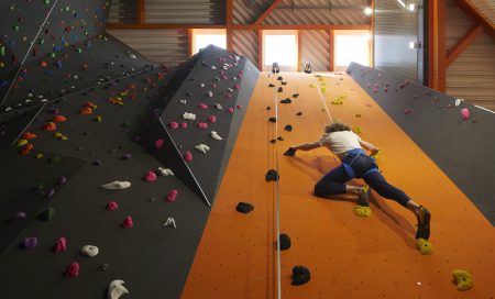 A view up a tall climbing wall with a climber on the wall