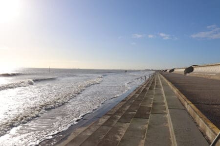 A concrete promenade with stone steps leading down into the sea