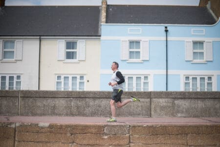 A man running on a promenade past a blue and a yellow house