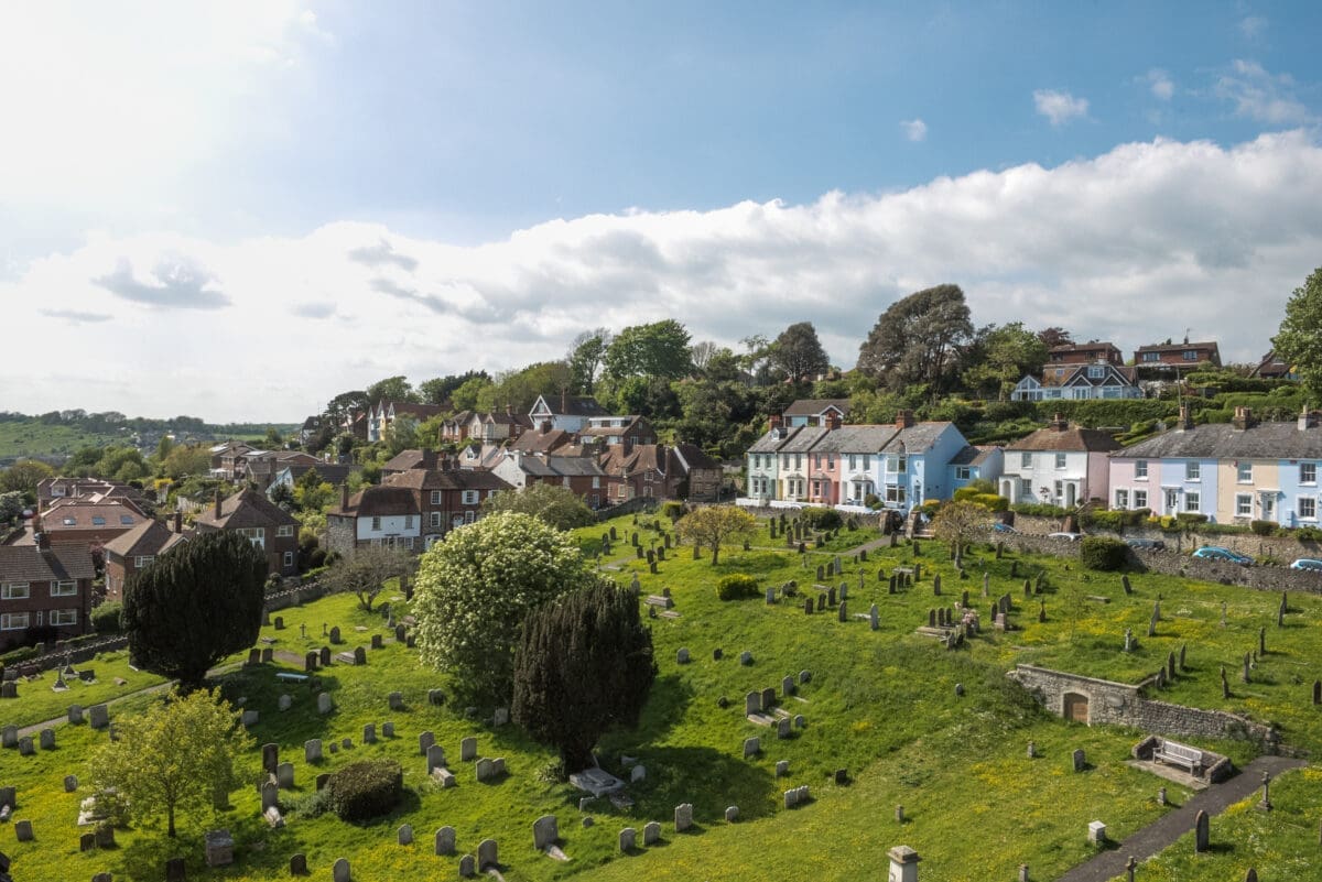 A large green cemetary stretches up a hill to a row of colourful houses