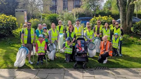 A group picture of Folkestone Wombles community litter picking volunteers with their equipment and hi visibility jackets
