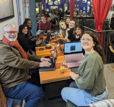 A group of smiling local professionals attending at flexible Work From Home Folk community group in a coffee shop in Folkestone