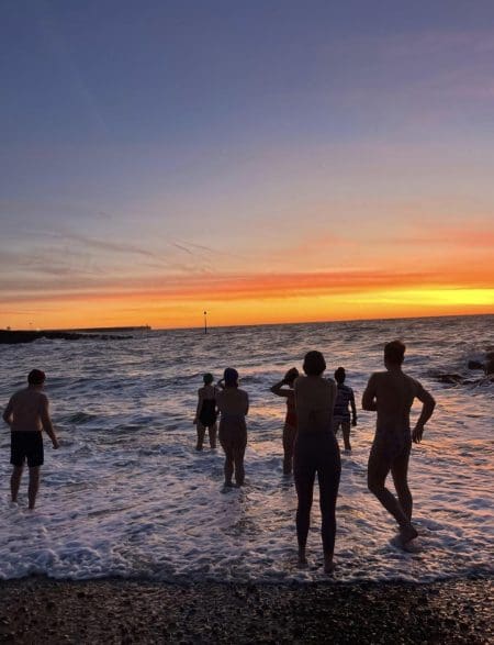 An image of the Wednesday Morning Dip Club community sea swimmers entering the ocean during the early morning in Folkestone