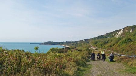 An image of a guided community explore across The Folkestone Warren which features mobility scooter and wheelchair from Wild With Wheels users viewing the coastal and country green area