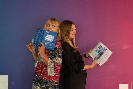 Two women reading the Book Festival Brochure